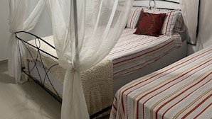 A room with a four-poster canopy bed, a smaller adjacent bed, and a nightstand. - Desfrute dessa maravilha. (Angra dos Reis)