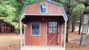 Une petite cabane en bois avec une véranda, une porte et une fenêtre.
