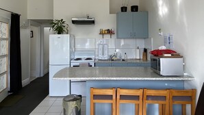 A kitchen with a central island, white appliances, and a blue cabinet. - Bayview house in Oriental Parade  (Wellington)