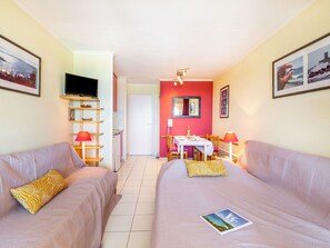 A room with two beds, a TV, a dining table, and a kitchen area. - Cosy apartment for 4 people with WIFI, pool, TV, terrace and pets allowed (Saint-raphaël)