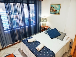 A hotel room with a bed, a nightstand, a lamp, and a painting on the wall.