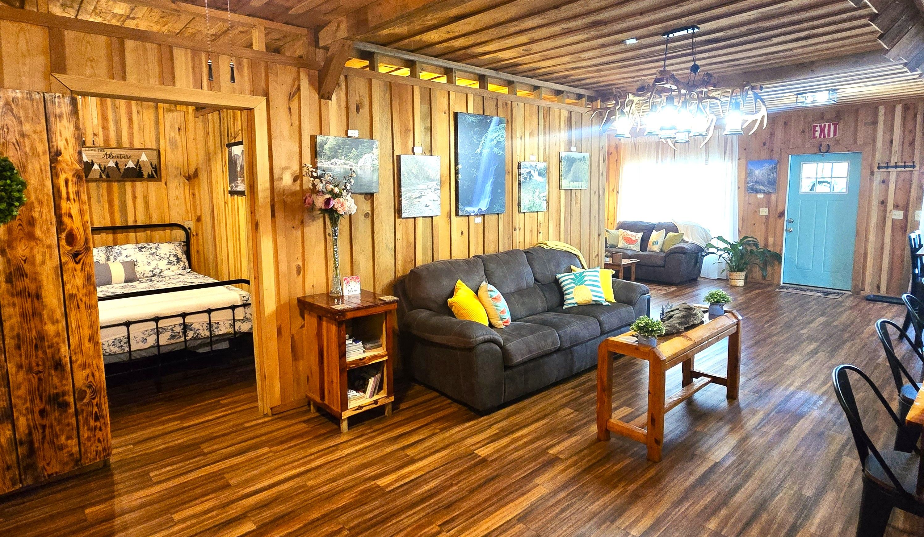 A wooden interior with a bed, sofa, and a dining area.
