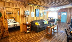 Een houten interieur met een bed, bank en een eethoek.