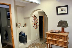 A hallway with a stone floor, wooden furniture, a wall-mounted decorative piece, and a framed picture of a bison.