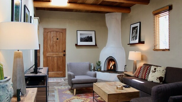 Un salon chaleureux avec une cheminée, un plafond en bois et un coin salon confortable.