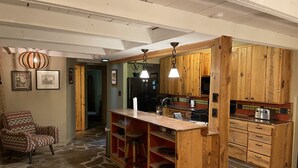 Une cuisine rustique avec des meubles en bois, un sol en pierre et un coin bar.