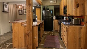 Une cuisine avec des meubles de rangement en bois, un réfrigérateur noir, une cuisinière et un four à micro-ondes.