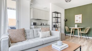 Un salon moderne avec un canapé gris, une table basse en bois et un coin repas comprenant une petite table et des chaises.