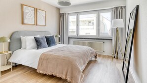 Une chambre moderne avec un lit, des tables de chevet, un radiateur et une fenêtre avec des rideaux.