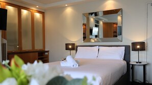 A hotel room with a large bed, two bedside lamps, a mirror, and a wardrobe. - KozyGuru | McMahons Point | Opera House View (McMahons Point)