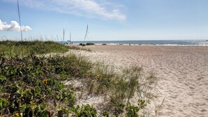 A sandy beach with sparse vegetation and a clear sky. - Oceanfront Condo w/ ocean view private balcony, on-site heated pool & hot tub (Cape Canaveral)