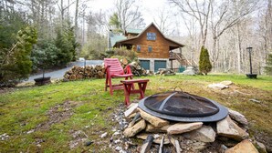 Une cabane avec un foyer extérieur, des sièges pour se détendre en plein air et une rivière en arrière-plan.