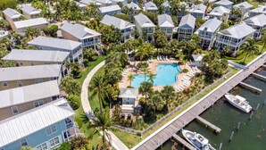 Un quartiere residenziale con diverse case a due piani, una piscina centrale e un molo con barche.