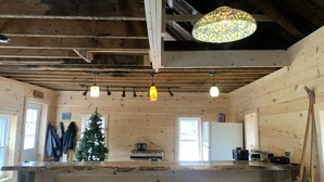 Un intérieur en bois comprenant un coin cuisine, un bar avec des tabourets et un luminaire suspendu.