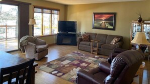 Ein Wohnzimmer mit Fernseher, zwei Sofas, einem Couchtisch und einem Essbereich mit Tisch und Stühlen.
