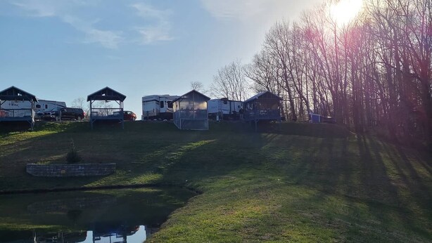 Een camping met campers en stacaravans, een klein vijvertje, en een heldere lucht.
