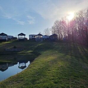 A campsite with RVs and mobile homes, a small pond, and a clear sky.