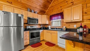 A kitchen with wooden cabinets, a stainless steel refrigerator, a microwave, an oven, and a dishwasher. - 1BR Cozy Cabin - Romantic, Hot Tub, Couples, RELAX in Pigeon Forge (Pigeon Forge)
