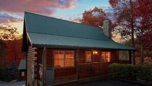 A log cabin with a metal roof, wooden exterior, and a porch. - 1BR Cozy Cabin - Romantic, Hot Tub, Couples, RELAX in Pigeon Forge (Pigeon Forge)