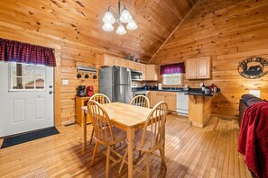 Cozy cabin interior with a dining table, kitchenette, and seating area.