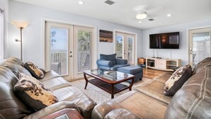 A spacious living room with leather sofas, a glass coffee table, and a flat-screen TV.