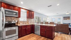 A modern kitchen with dark wood cabinets, stainless steel appliances, and a wooden floor.