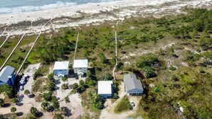 An aerial view of a coastal property with multiple buildings, a beach, and a mix of vegetation.