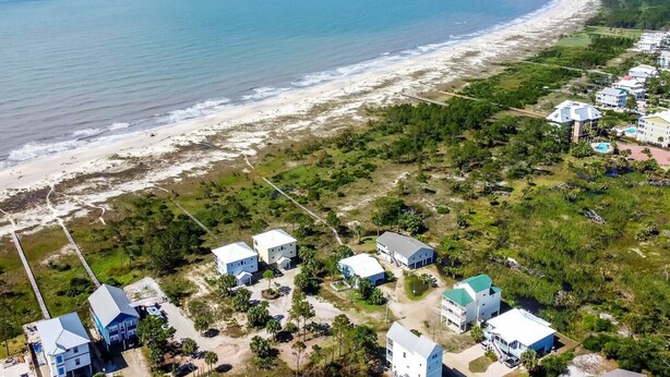An aerial view of a coastal area with a beach, houses, and a large building with a dome roof.