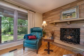 A room with a leather armchair, a fireplace, a chessboard, and a large window. - Sunset Ranch over Crab Creek (Penrose)