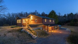 A two-story house with a covered porch, a front staircase, and a gravel driveway. - JB`s Place - One Home with Two Living Spaces! (Brevard)