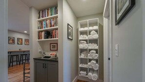 A hallway with a kitchen area, a bookshelf, and a towel rack. - JB`s Place - One Home with Two Living Spaces! (Brevard)