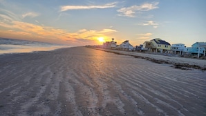 Une plage au coucher du soleil, des maisons le long du rivage et une jetée.