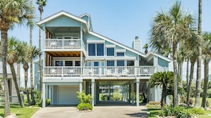 Une maison à deux étages avec un balcon, entourée de palmiers.