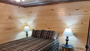 A wooden-paneled room with a bed, two nightstands, and lamps. - Paradise Valley private with a Romatic Stream (Dahlonega)