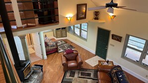 A spacious living area with a fireplace, leather furniture, and large windows. - Paradise Valley private with a Romatic Stream (Dahlonega)