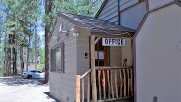 Un pequeño edificio de madera con un letrero que dice "OFFICE" en la entrada, rodeado de árboles.