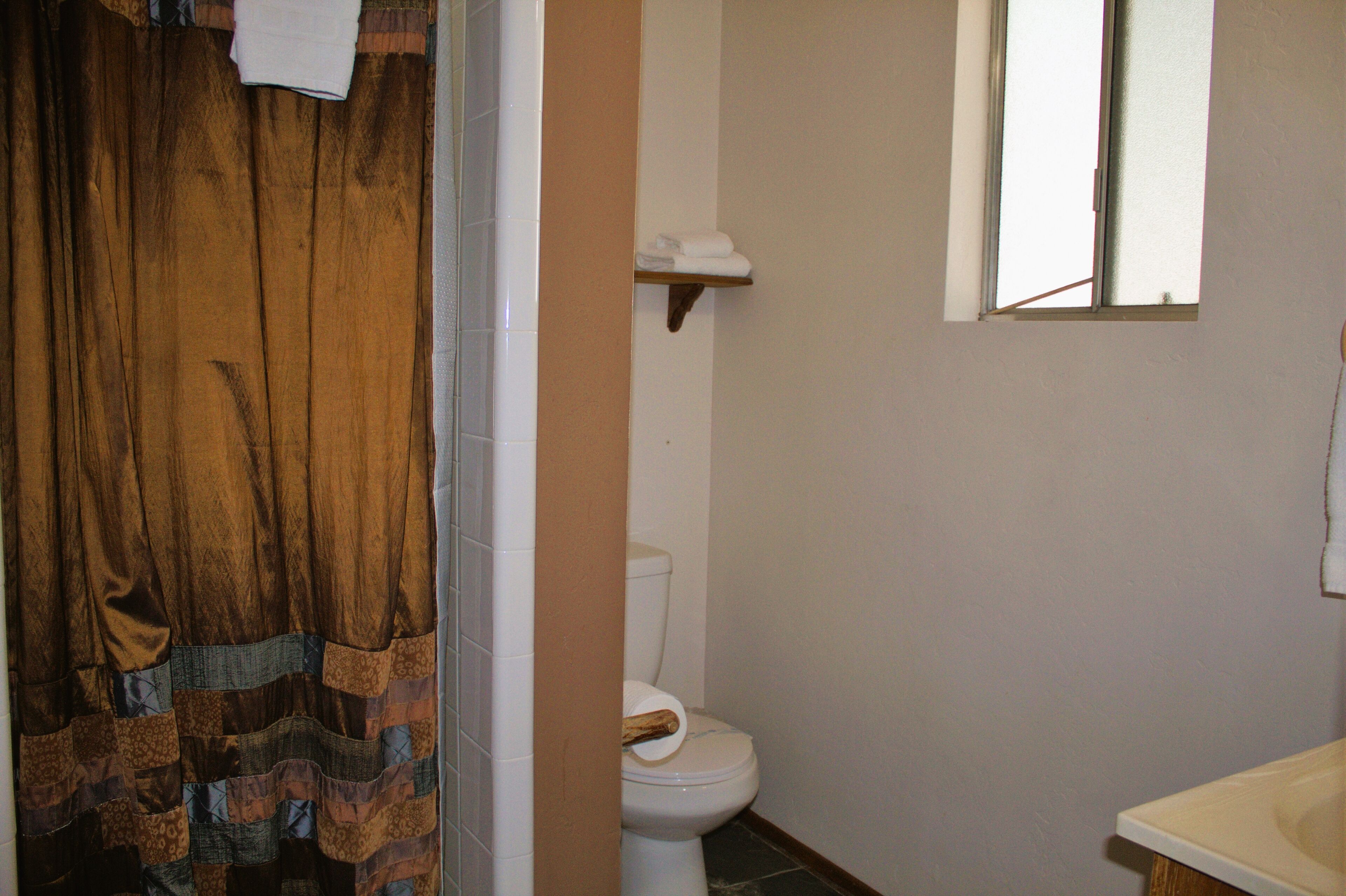 Ein Badezimmer mit Toilette, Waschbecken, Fenster und einer Duschvorhang.