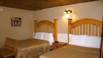 A room with two wooden beds, a wooden chair, and a wall-mounted light fixture.