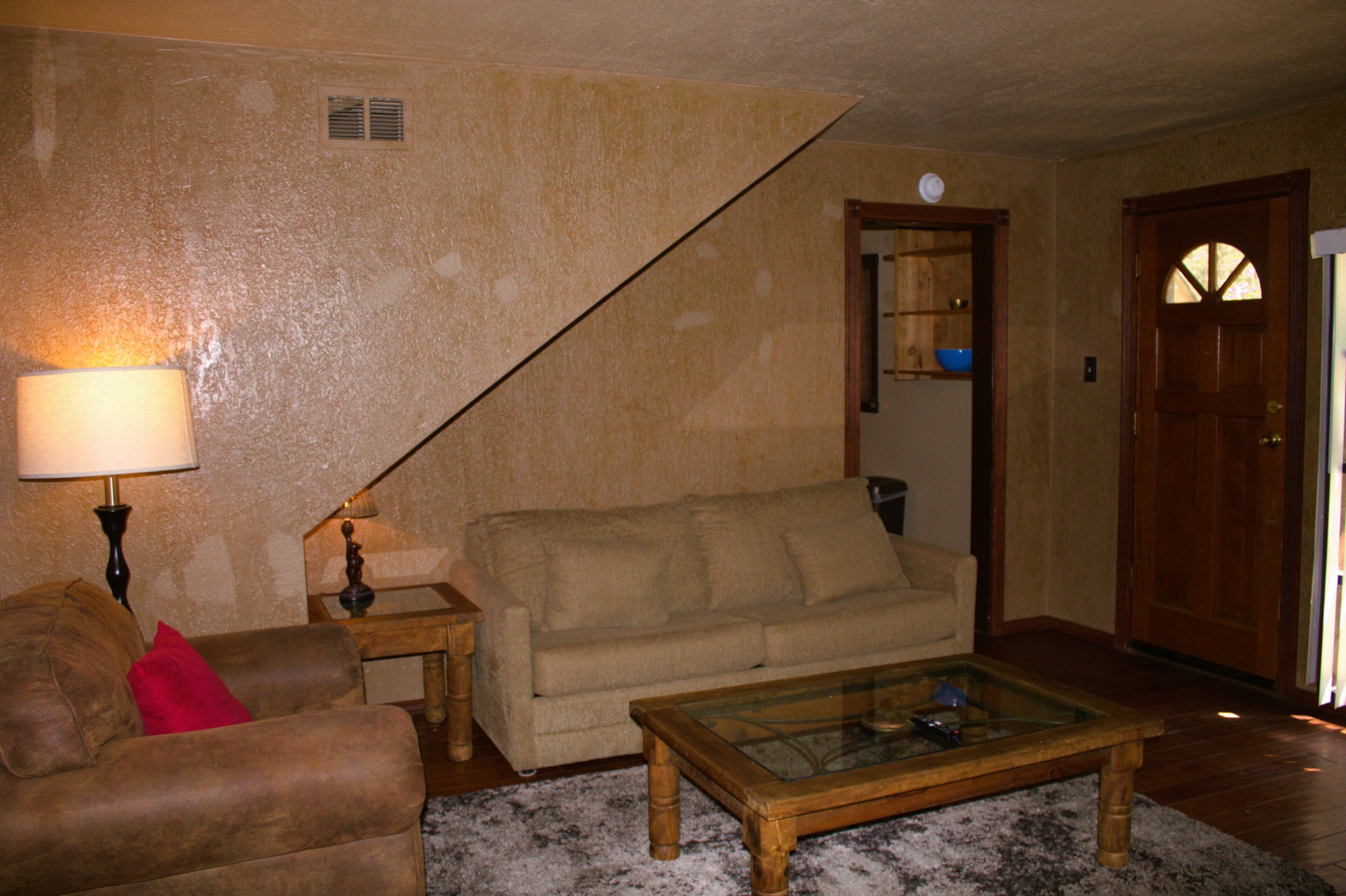 A living room with a sofa, a coffee table, and a lamp.
