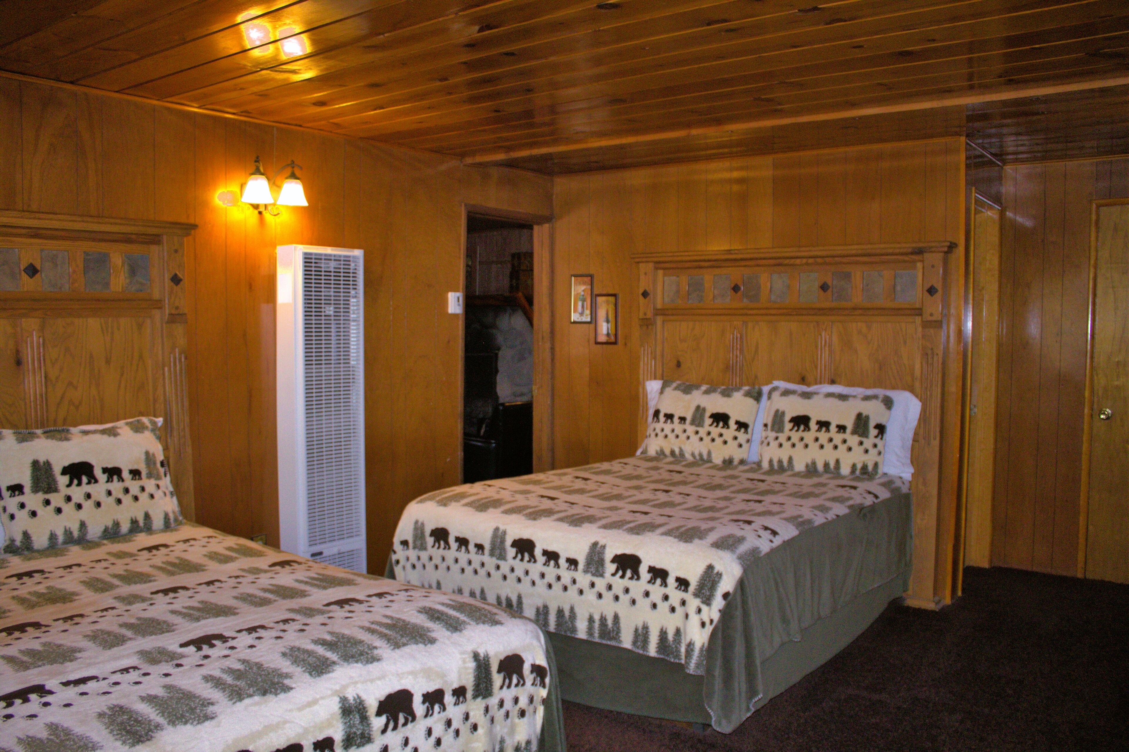 A room with two beds, wooden walls, and a door.