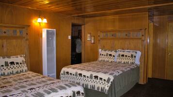 A room with two beds, wooden walls, and a door.
