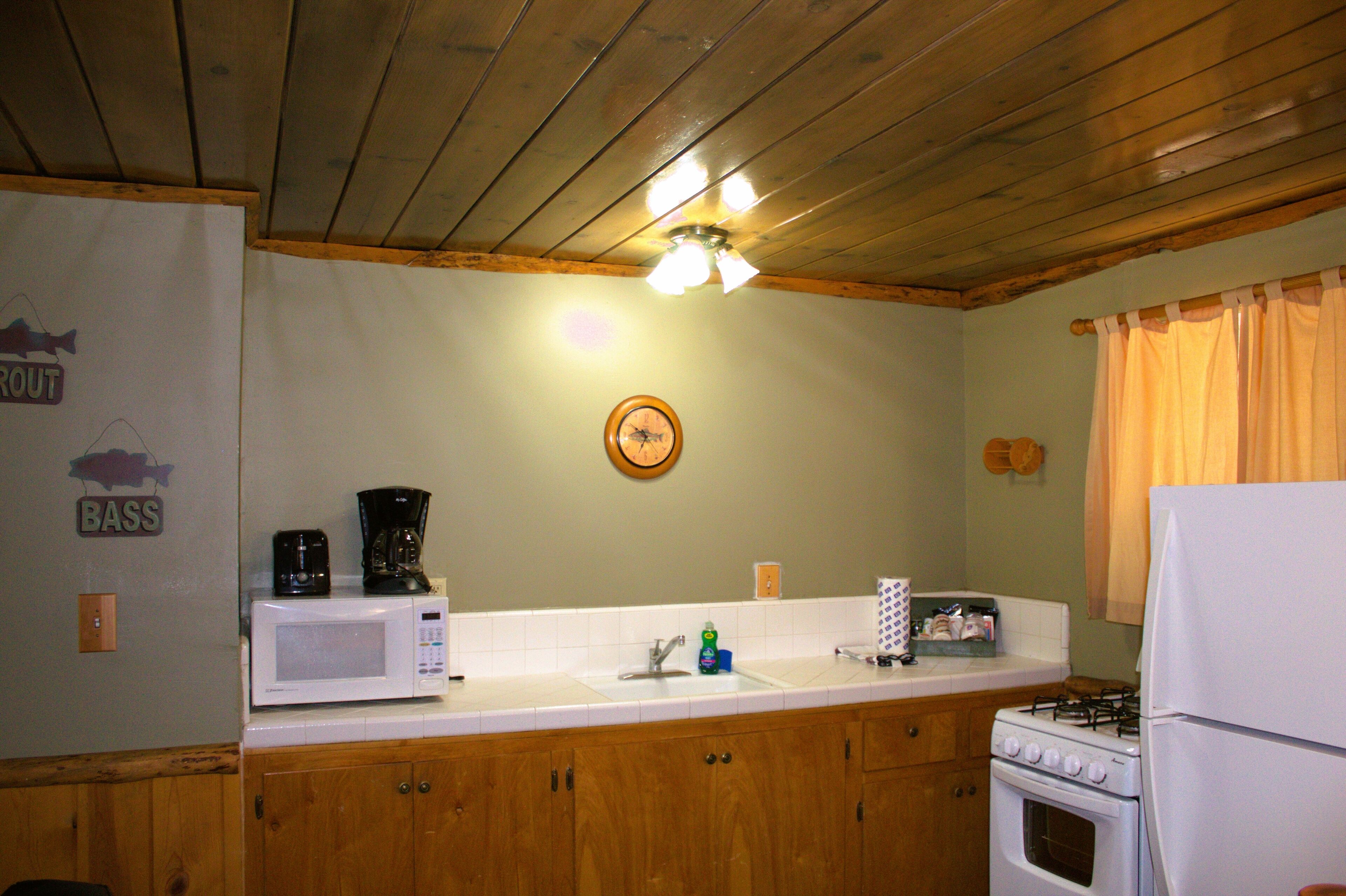 A kitchen with wooden cabinets, a white stove, a microwave, and a sink.