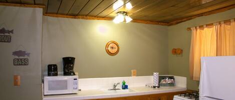 A kitchen with wooden cabinets, a white stove, a microwave, and a sink.