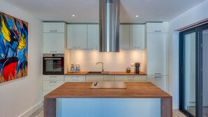 A modern kitchen with a central island, stainless steel range hood, and white cabinetry. - One bedroom loft marina Anse Marcel (Cul-de-Sac)