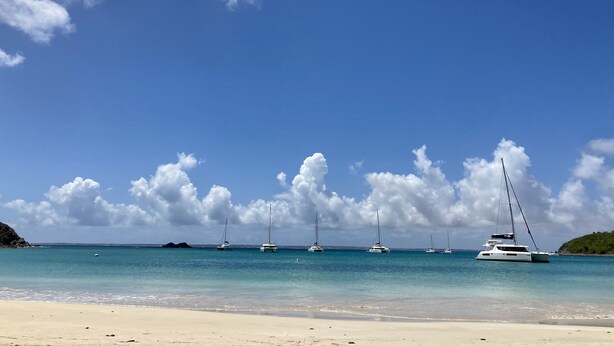 A beach with several sailboats anchored in the water, a sandy shore, and a clear blue sky with clouds. - One bedroom loft marina Anse Marcel (Cul-de-Sac)