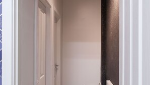 Ein Flur mit weißen Türen, einem dunklen Boden und einem gemusterten Teppich.