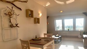 Un comedor con mesa de madera, sillas y una rama decorativa en la pared.