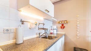 Een keuken met een granieten aanrecht, een roestvrijstalen spoelbak en een keukenpapierhouder.