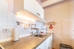 A kitchen with a granite countertop, stainless steel sink, and a paper towel dispenser. - Haevn by the Sea Retreat, Apartment Rosenquarz (Reußenköge)