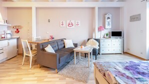 Un saló modern amb un sofà, una taula de dinar, un televisor i una zona de cuina.